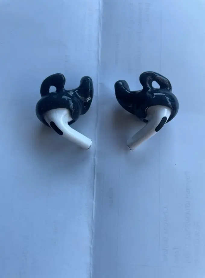 A pair of black custom Big Ear adapters fitted onto Apple AirPods Pro