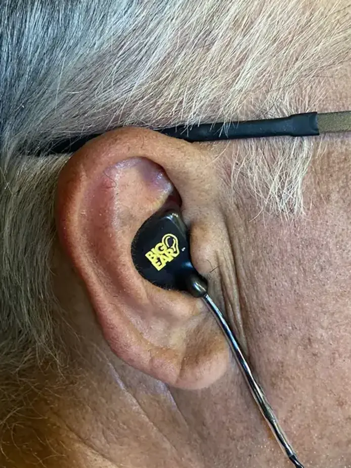 A customer wearing a black-faceplate Big Ear custom IEM
